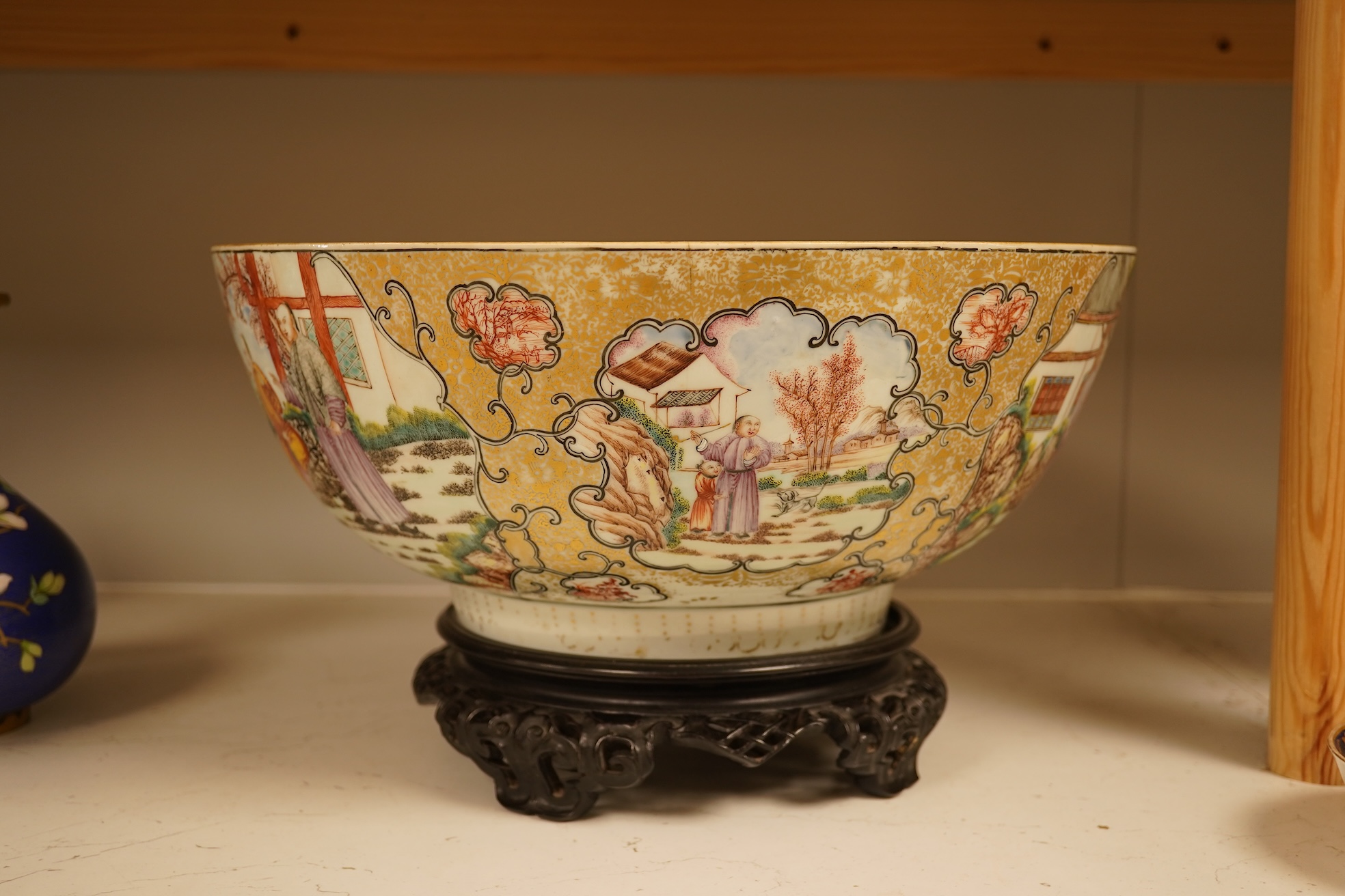 An 18th century Chinese famille rose figural bowl, on wooden stand, 34cm diameter.